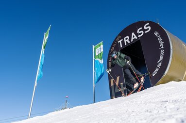 Skifahrer startet durch das markierte Portal der Trass auf der Schmittenhöhe in die Abfahrt. | © Schmittenhöhebahn AG, MR Offenblende