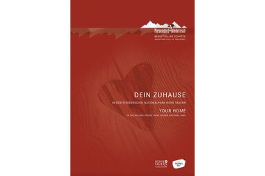 Titelbild des Unterkunftsverzeichnisses von Piesendorf und Niedernsill mit einem herzförmigen Ausschnitt in einer Holzoberfläche. | © TVB Piesendorf Niedernsill