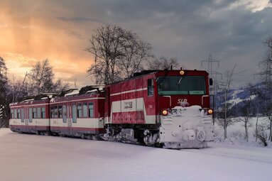 Pinzgauer Lokalbahn fährt bei tief stehender Sonne durch eine verschneite Winterlandschaft. | © Florian Knapp