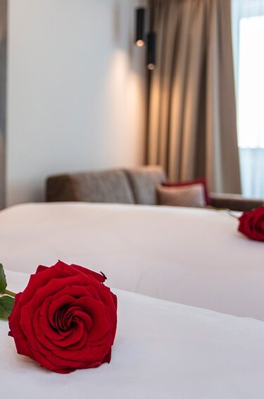 Zimmer im Klawunn Hotel & Apartment mit zwei Betten, weißer Bettwäsche, roten Kissen und Rosen. | © nikolaus faistauer photography