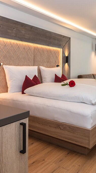 Zimmer im Klawunn Hotel & Apartment mit Doppelbett, Sitzbereich, Schreibtisch, großen Fenstern und roten Akzenten. | © nikolaus faistauer photography