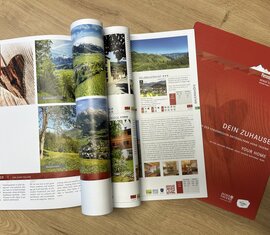 Open accommodation directory and red Piesendorf and Niedernsill brochure on a wooden table | © TVB Piesendorf Niedernsill