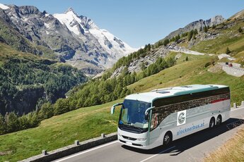 A bus travels along the Grossglockner High Alpine Road with glaciated mountains in the background. | © Großglockner Hochalpenstraße AG, Foto Michael Königshofer