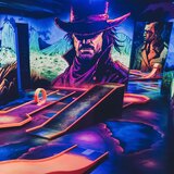 Indoor mini golf course with several lanes, colourful lighting and large Western-style comic illustrations. | © Wildpark Ferleiten 