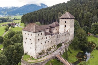 Burg Kaprun mit Mauern und Turm vor einem bewaldeten Hang. Im Hintergrund liegen das Tal und Berge. | © Arne Mueseler - arne-mueseler.com