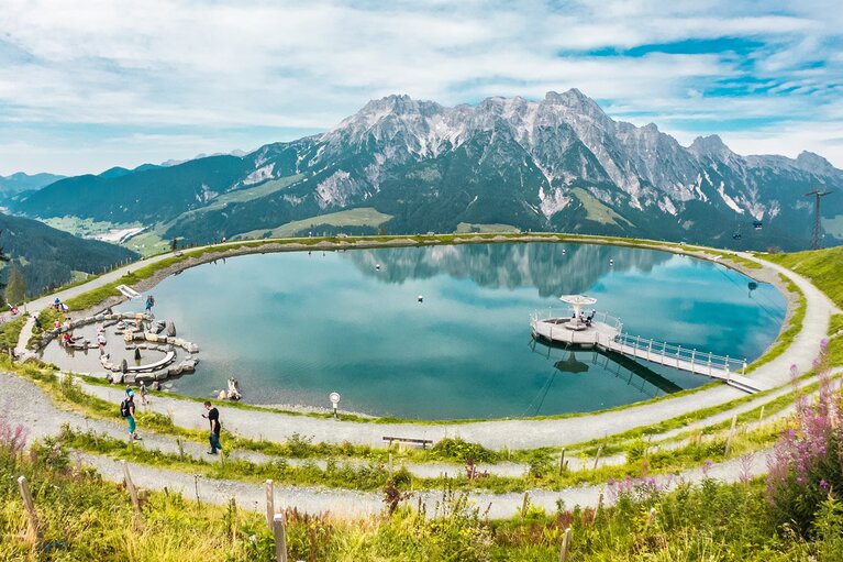 Stille Wasser am Asitz in Leogang mit Bergsee, Steg und Wegen vor dem Bergpanorama. | © Michael Geißler