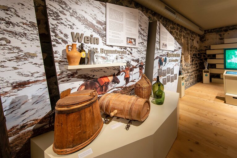 Exhibition room at the Felberturm Museum with historic wooden containers, glass bottles, display panels and a digital media station. | © Foto Franz Reifmüller