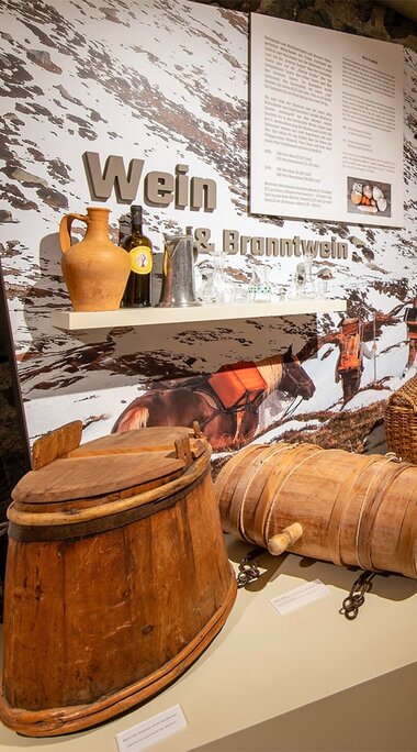 Exhibition room at the Felberturm Museum with historic wooden containers, glass bottles, display panels and a digital media station. | © Foto Franz Reifmüller