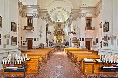 Interior of Maria Kirchental with wooden pews, central aisle, ornate altar, pulpit and religious paintings. | © Wanderdörfer