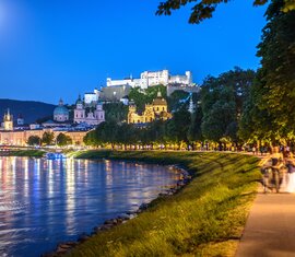 Salzburg bei Nacht mit Salzach, beleuchteter Altstadt und Festung Hohensalzburg unter dem Mond. | © Tourismus Salzburg, Foto Breitegger Günter