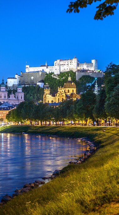 Salzburg bei Nacht mit Salzach, beleuchteter Altstadt und Festung Hohensalzburg unter dem Mond. | © Tourismus Salzburg, Foto Breitegger Günter