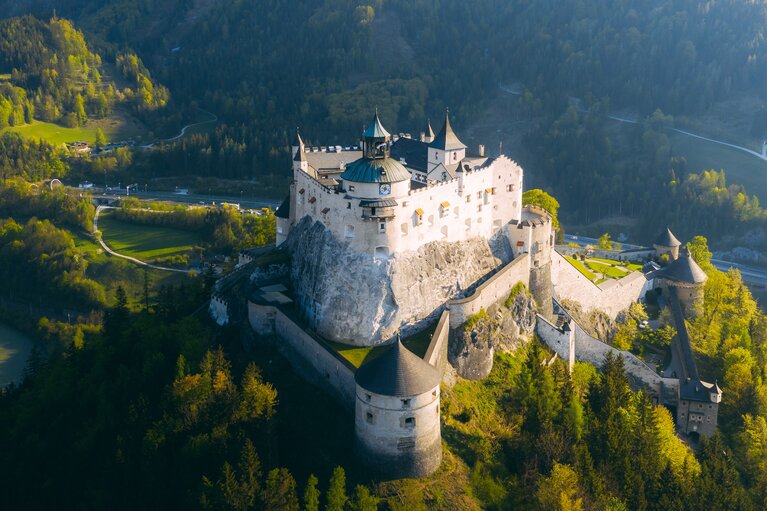 Luftaufnahme der Burg Hohenwerfen auf einem Felsen, umgeben von bewaldeten Hängen. | © SalzburgerLand Tourismus