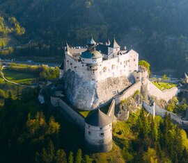 Aerial view of Hohenwerfen Castle on a rocky outcrop, surrounded by forested slopes. | © SalzburgerLand Tourismus