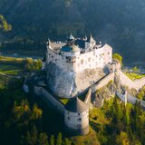 Aerial view of Hohenwerfen Castle on a rocky outcrop, surrounded by forested slopes. | © SalzburgerLand Tourismus