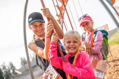 Three children at a rope play station on Schmidolin’s Feuertaufe on the Schmittenhöhe. | © Schmittenhöhebahn AG