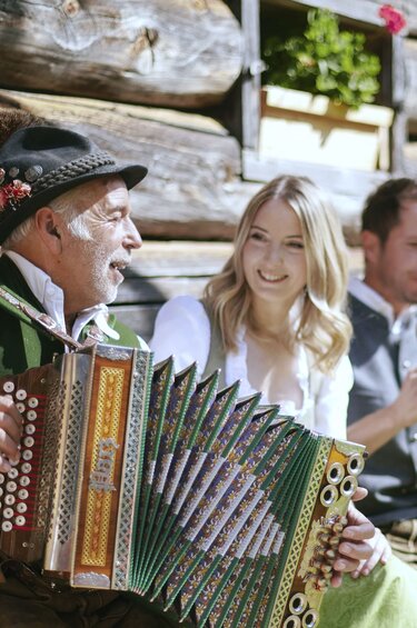 Musikgruppe in Tracht spielt vor einem Holzgebäude Ziehharmonika, Klarinette und Blechblasinstrumente. | © SalzburgerLand Tourismus