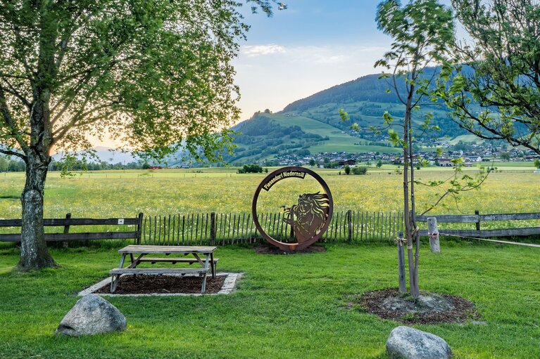 Isonta photo point with a bench by a meadow, overlooking Piesendorf-Niedernsill and the surrounding mountain slopes. | © TVB Piesendorf Niedernsill, Foto Lichtfarben