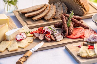 Jause mit Brot, Käse, Würsten, Speck, Tomaten, Radieschen und Zwiebeln auf Holzbrettern angerichtet. | © SalzburgerLand Tourismus 