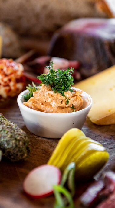 Brettljause with assorted cheeses, sausage, bacon, spread, pickles and radishes served on a wooden board. | © SalzburgerLand Tourismus
