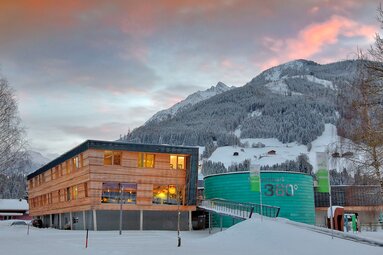 Nationalpark Worlds Hohe Tauern building with the words “Nationalpark 360°” in front of snow-covered mountains. | © Ferienregion Nationalpark Hohe Tauern