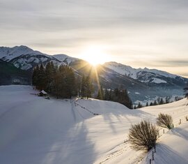 Verschneite Landschaft am Naglköpfl mit Bäumen und umliegenden Bergen bei tief stehender Sonne. | © Ferienregion Nationalpark Hohe Tauern, Foto David Innerhofer