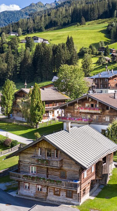 View of Aisdorf near Niedernsill with traditional wooden houses, meadows and forested mountain slopes. | © TVB Piesendorf Niedernsill, Foto Harry Liebmann 