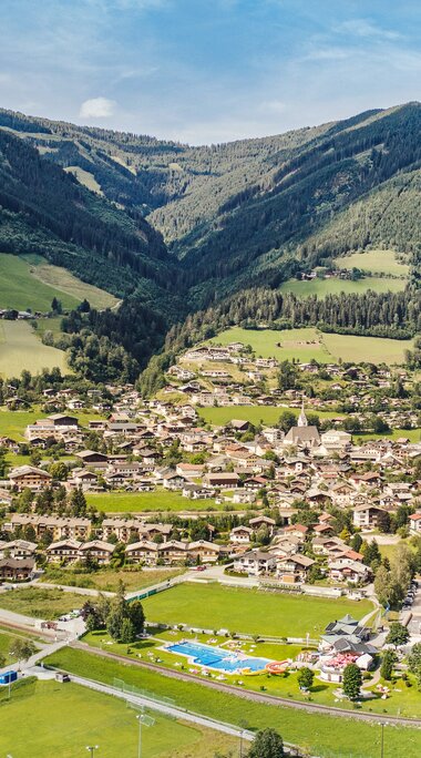 Luftaufnahme von Piesendorf mit Ortszentrum, Wiesen und bewaldeten Berghängen im Hintergrund. | © TVB Piesendorf Niedernsill, Foto Harry Liebmann 