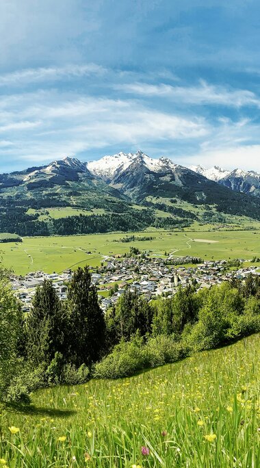 Blick über Piesendorf und das Salzachtal mit Wiesen, Wäldern und teils schneebedeckten Bergen. | © TVB Piesendorf Niedernsill, Foto Harry Liebmann 