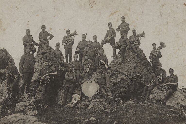 Historische Aufnahme von 1917 mit uniformierten Musikern auf Felsen, mehreren Blechblasinstrumenten und einer großen Trommel. | © TVB Piesendorf Niedernsill