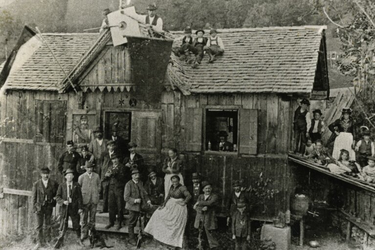 Historische Aufnahme des Schießstands Hochbürgl mit zahlreichen Erwachsenen und Kindern vor und auf dem Holzgebäude. | © TVB Piesendorf Niedernsill