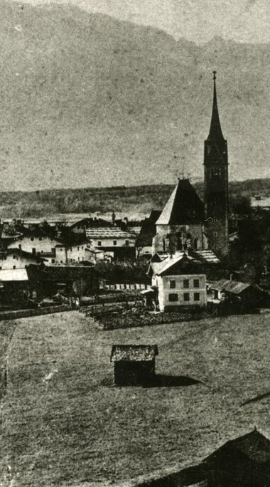 Historische Ansicht von Piesendorf aus dem Jahr 1914 mit Kirche, Häusern und Wiesen vor den umliegenden Bergen. | © TVB Piesendorf Niedernsill