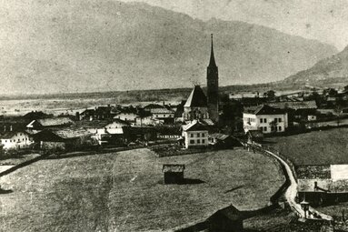 Historische Ansicht von Piesendorf aus dem Jahr 1914 mit Kirche, Häusern und Wiesen vor den umliegenden Bergen. | © TVB Piesendorf Niedernsill