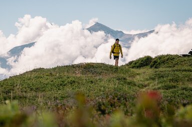 Wanderer auf dem Hohe Tauern Panorama Trail, Etappe 09, vor Berggipfeln und Wolken. | © Ferienregion Nationalpark Hohe Tauern, Gerald Demolsky