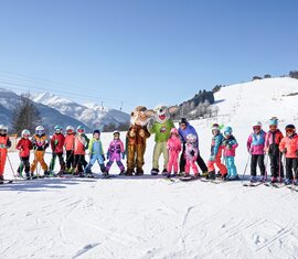 Children in ski gear with two animal mascots on the ski slope at Erlebnisberg Naglköpfl in Piesendorf. | © TVB Piesendorf Niedernsill, Foto Harry Liebmann 