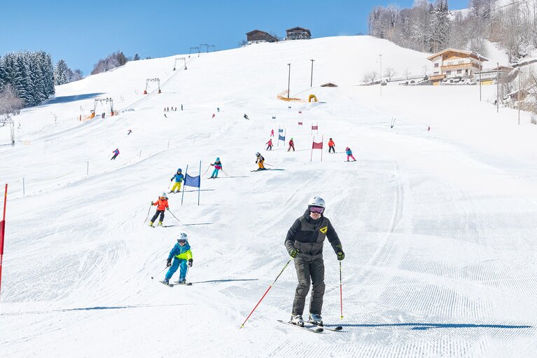 Skifahrende auf der Skipiste am Erlebnisberg Naglköpfl in Piesendorf, darunter eine erwachsene Person und ein Kind. | © TVB Piesendorf Niedernsill, Foto Harry Liebmann 