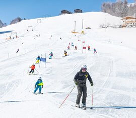 Skifahrende auf der Skipiste am Erlebnisberg Naglköpfl in Piesendorf, darunter eine erwachsene Person und ein Kind. | © TVB Piesendorf Niedernsill, Foto Harry Liebmann 