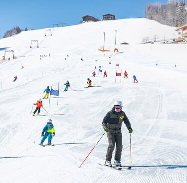 Skifahrende auf der Skipiste am Erlebnisberg Naglköpfl in Piesendorf, darunter eine erwachsene Person und ein Kind. | © TVB Piesendorf Niedernsill, Foto Harry Liebmann 