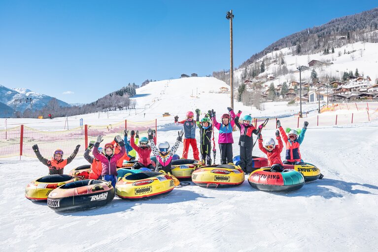 Gruppe von Kindern mit bunten Snowtubes auf einer verschneiten Fläche am Erlebnisberg. | © TVB Piesendorf Niedernsill, Foto Harry Liebmann