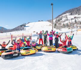 Gruppe von Kindern mit bunten Snowtubes auf einer verschneiten Fläche am Erlebnisberg. | © TVB Piesendorf Niedernsill, Foto Harry Liebmann