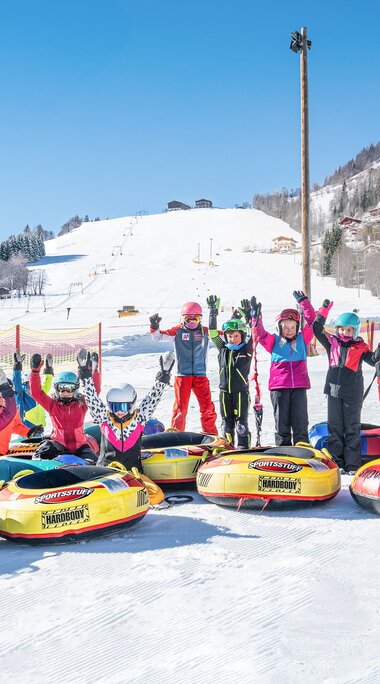 Group of children with colourful snow tubes on a snow-covered area at the Erlebnisberg. | © TVB Piesendorf Niedernsill, Foto Harry Liebmann