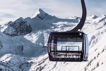 ALT text English Kitzsteinhorn Explorer cabin in front of snow-covered peaks and mountain slopes. | © Kitzsteinhorn