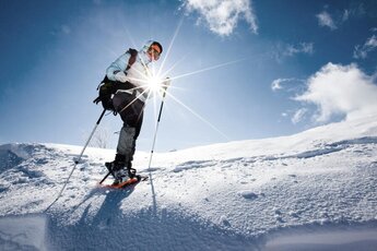 Person mit Schneeschuhen und Stöcken wandert bei Sonnenschein über einen verschneiten Hang am Kitzsteinhorn. | © Zell am See-Kaprun Tourismus