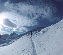 Ski tourer ascends a track across a snow-covered mountain slope at the Kitzsteinhorn. | © Stephan Obenaus
