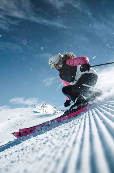 Skifahrerin fährt eine Kurve auf einer präparierten Piste am Kitzsteinhorn und wirbelt dabei Schnee auf. | © Kitzsteinhorn