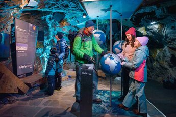 Family explores an interactive exhibition with globes at Gipfelwelt 3000 on the Kitzsteinhorn. | © Kitzsteinhorn