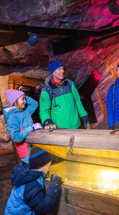 Family viewing an illuminated chest in an exhibition about Tauern gold and silver at Kitzsteinhorn. | © Kitzsteinhorn