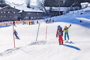 Children skiing on a groomed slope with small waves and a practice area. | © Lichtfarben
