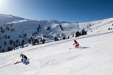 Two people skiing on a groomed slope at Wildkogel-Arena Neukirchen & Bramberg. | © Wildkogel-Arena Neukirchen & Bramberg