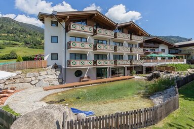 Klawunn Hotel & Apartment with balconies, garden and swimming pond in front of green mountain slopes. | © Klawunn