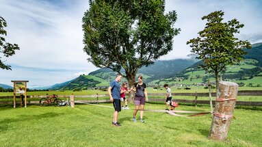 Family with two children at a slackline on a meadow, with bicycles and an Alpine valley in the background. | © TVB Piesendorf Niedernsill, Foto Lichtfarben